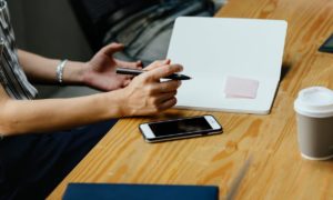 A person holding a pen with hand on the table 